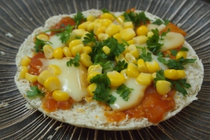 Pita pizza with tomato sauce, cheese, corn, and parsley